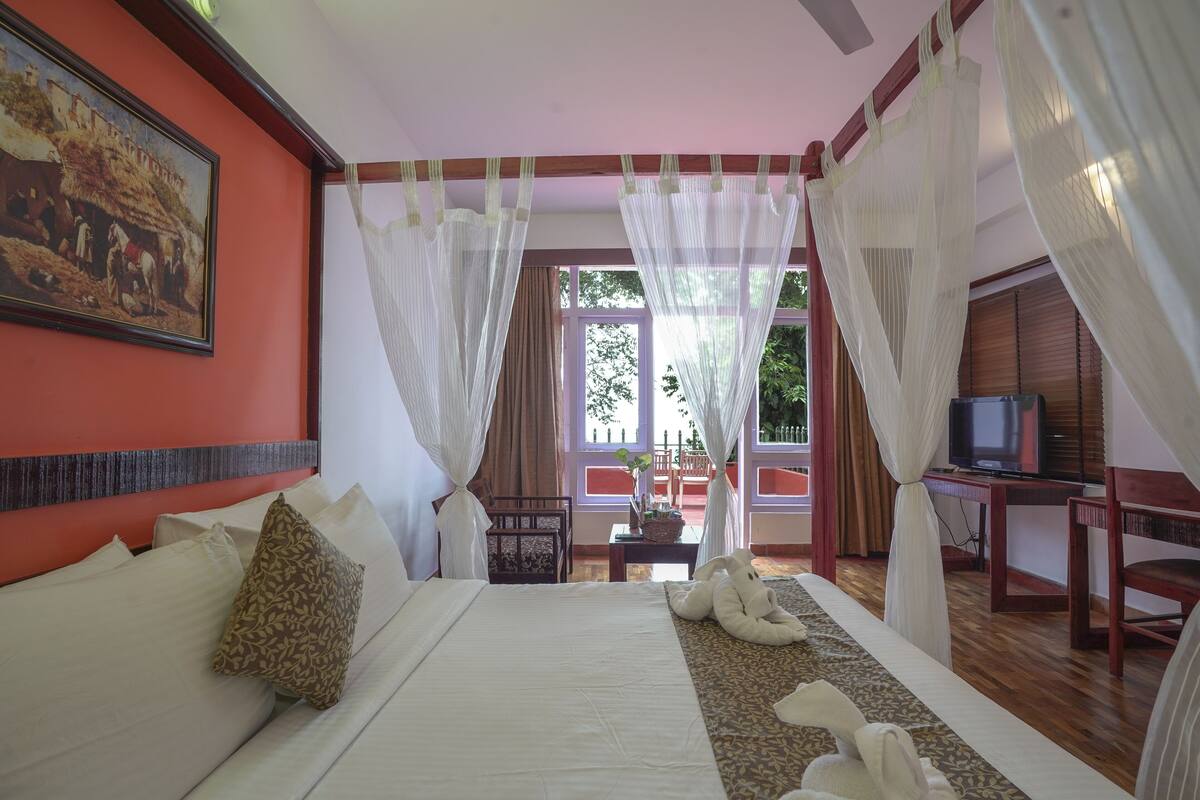 Una habitación de hotel con cama, televisión y balcón con cortinas.