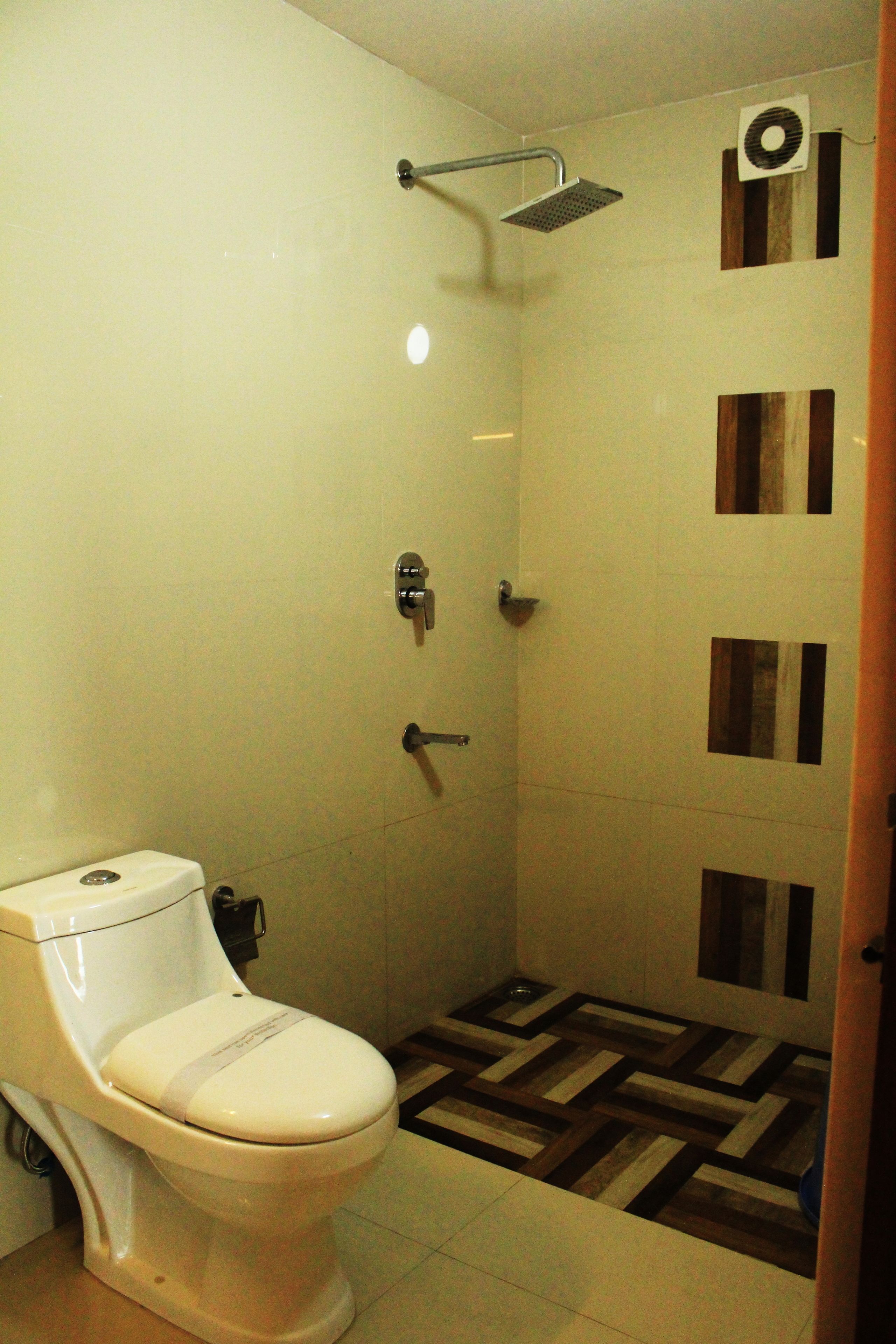 A bathroom with a toilet, shower, and a tiled floor with a geometric pattern.
