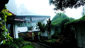 A house with a garden, a staircase leading to the entrance, and a view of the surrounding greenery. - Bella Vista Resort (Devikolam)