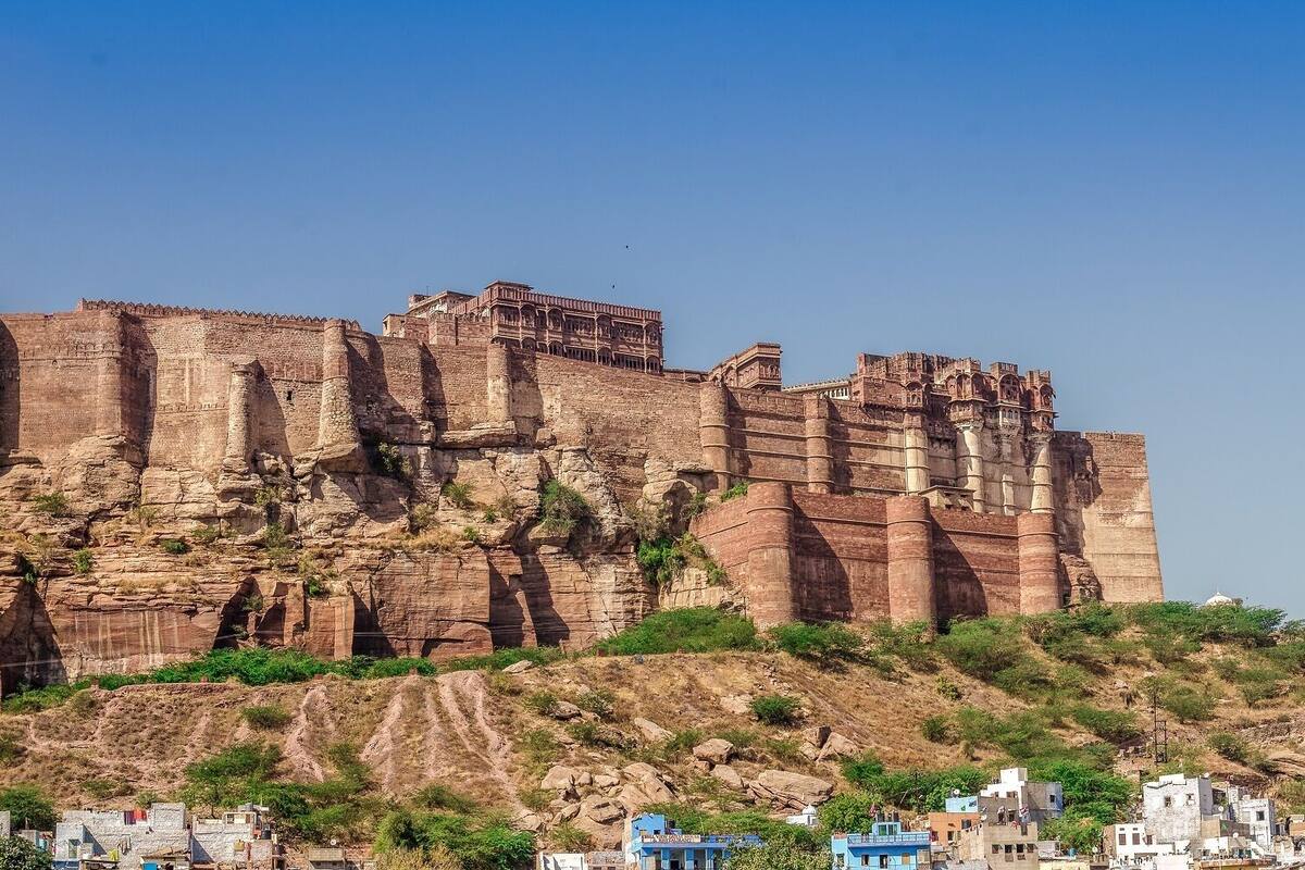 A historic fort with multiple towers and a large central structure, surrounded by a hilly landscape with sparse vegetation.