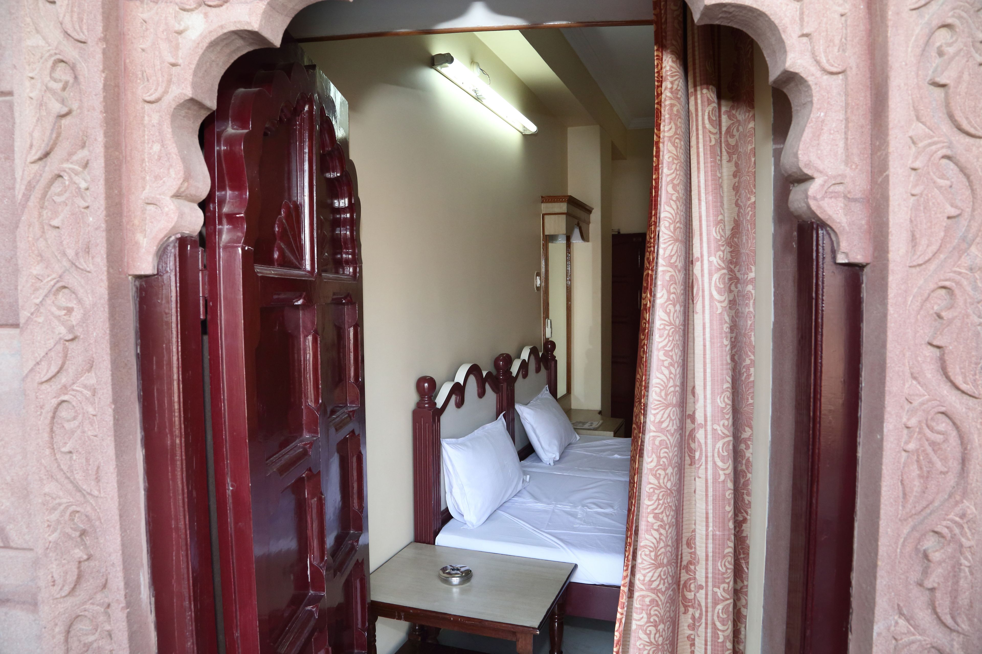 A room with a bed, a small table, and a mirror.