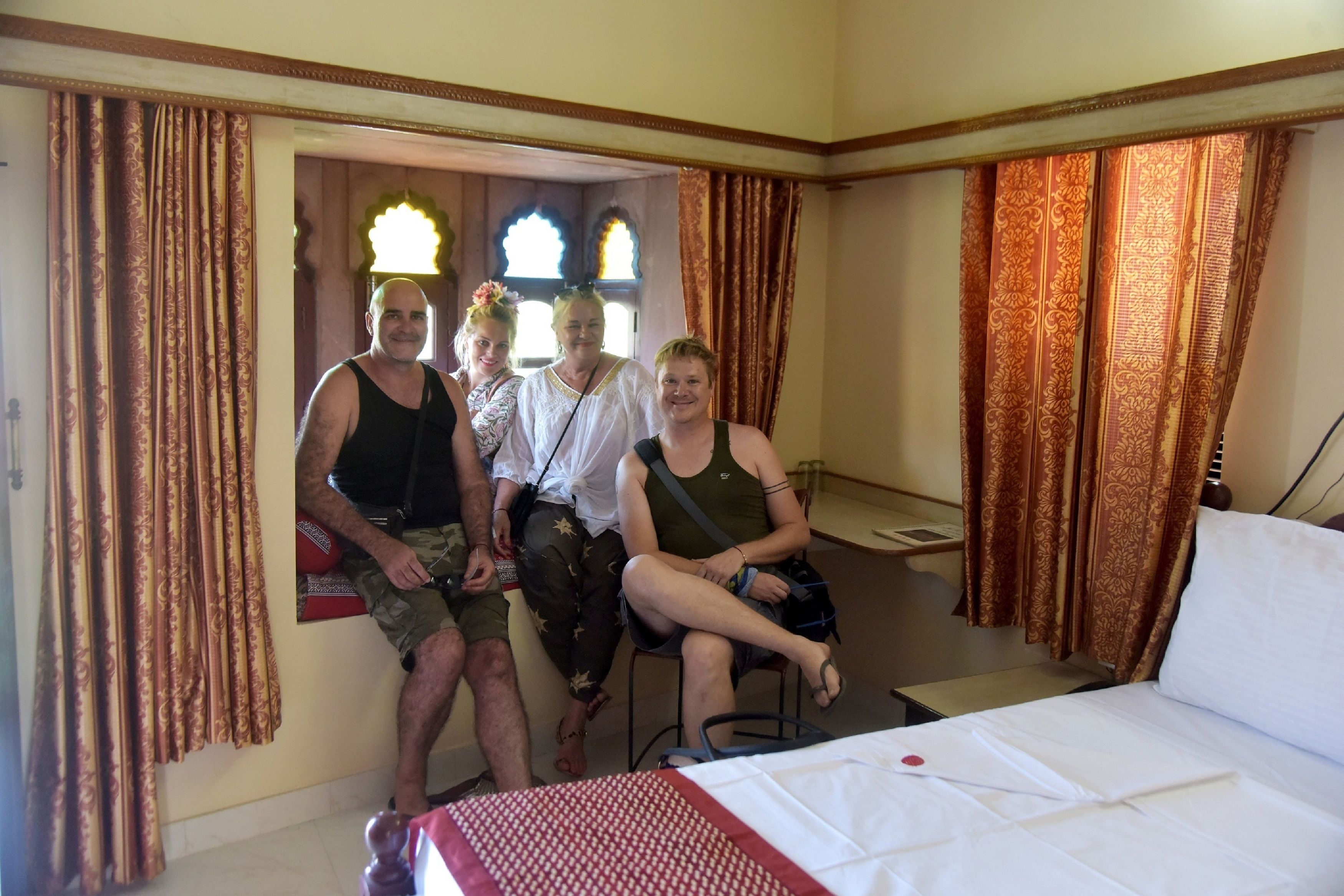 Una habitación de hotel con una cama, una silla y un ventanal con cortinas.