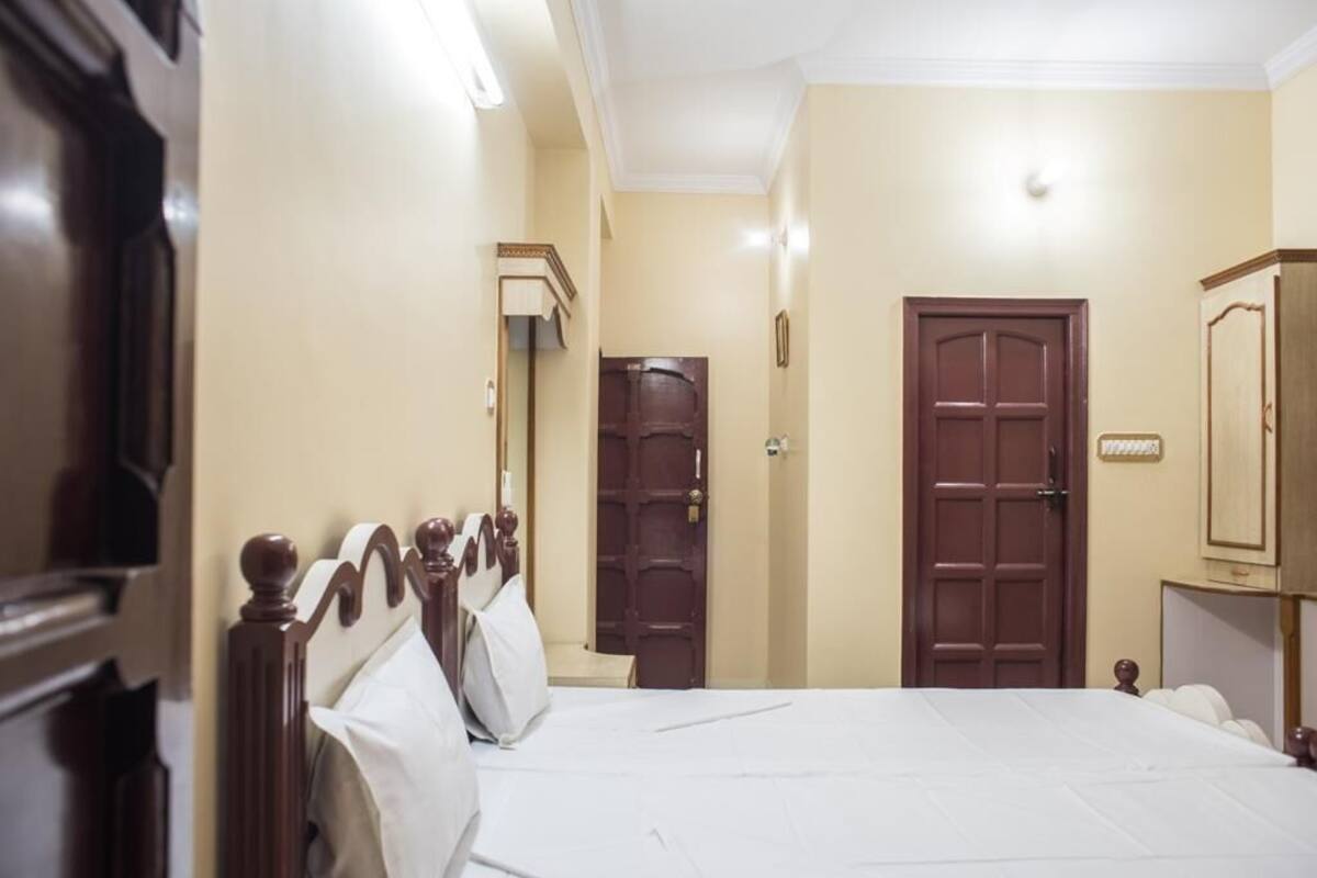 A hotel room with a bed, a wooden wardrobe, a door, and a mirror.