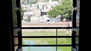 An open doorway with a view of a cityscape, a body of water, and a hill in the background. - Jee Ri Haveli (Jodhpur)