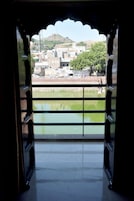 Un umbral abierto con vistas a un paisaje urbano, una masa de agua y una colina al fondo.
