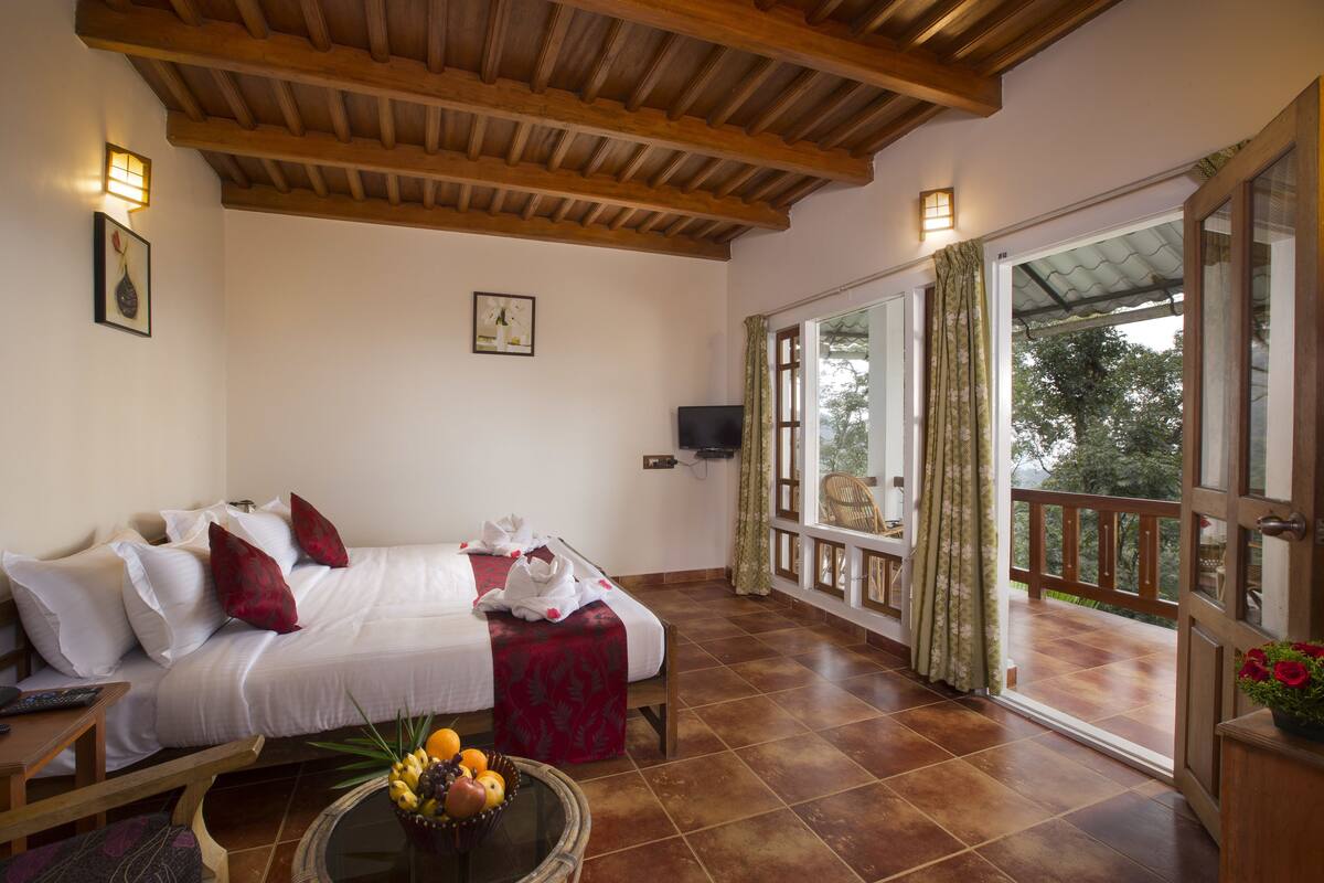 A bedroom with a bed, a bedside table, a TV, and a balcony with a view.