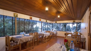 A dining area with wooden tables and chairs, large windows, and a wooden ceiling. - Bracknell Forest (Udumbanchola)