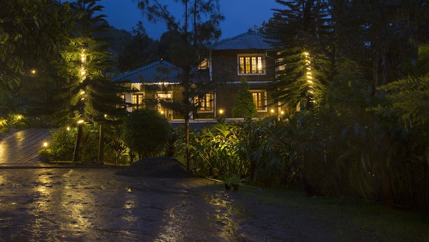A two-story house with a tiled roof, surrounded by dense vegetation and illuminated by string lights. - Bracknell Forest (Udumbanchola)