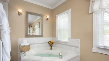 Un baño con una bañera grande, un espejo y una ventana con persianas.