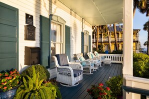 A porch with wicker rocking chairs, a mailbox, and a plaque indicating membership in a registry.