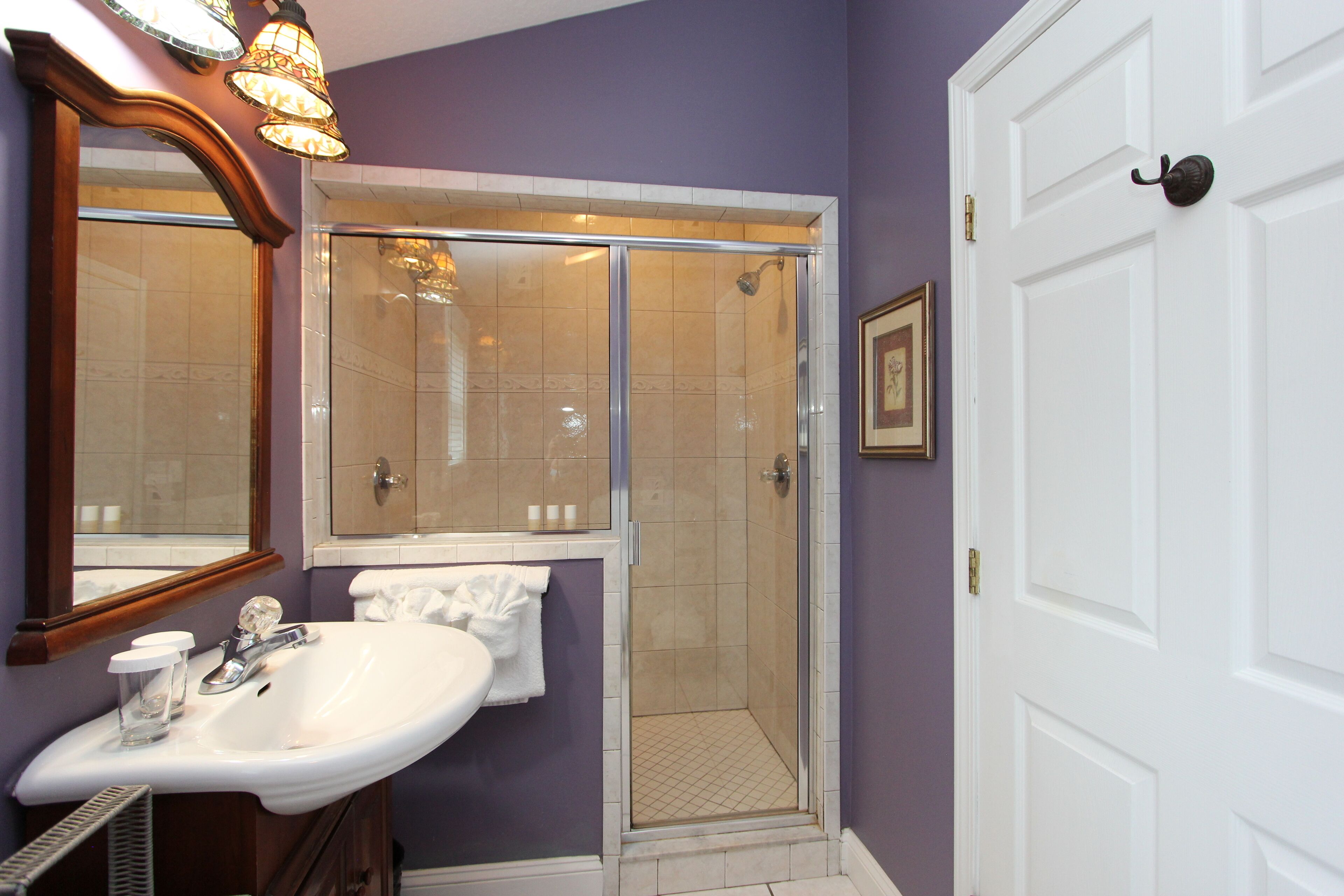 A bathroom with a white sink, a glass shower enclosure, and a door with a handle.