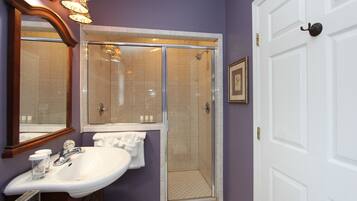A bathroom with a white sink, a glass shower enclosure, and a door with a handle.