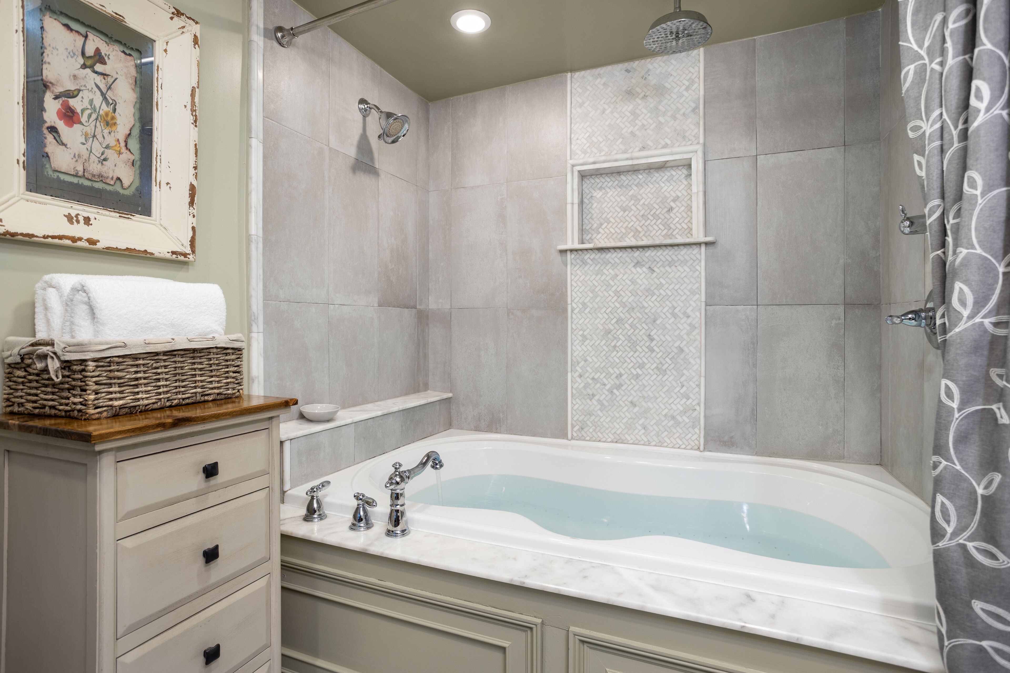 A bathroom with a bathtub, a shower, and a sink. There is a towel rack and a basket on the counter.
