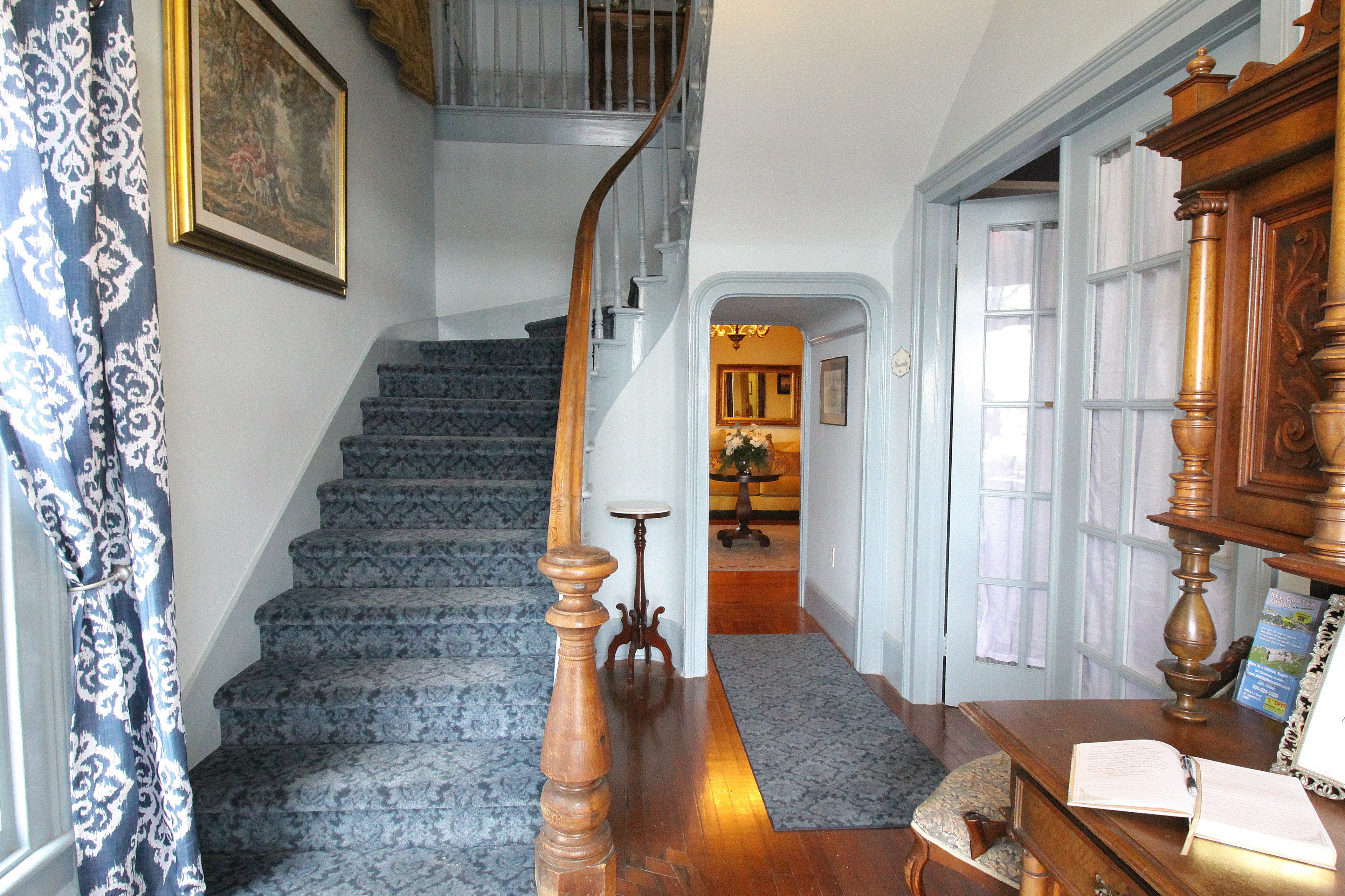 A staircase with a wooden handrail, a patterned carpet, and a wooden side table with a book and a picture frame.