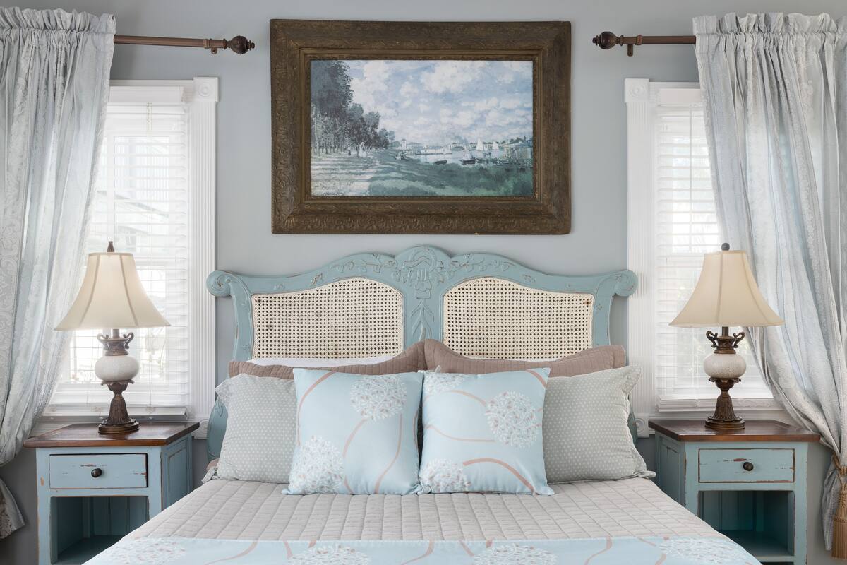 Un dormitorio con cama, dos mesitas de noche, un cuadro y cortinas.