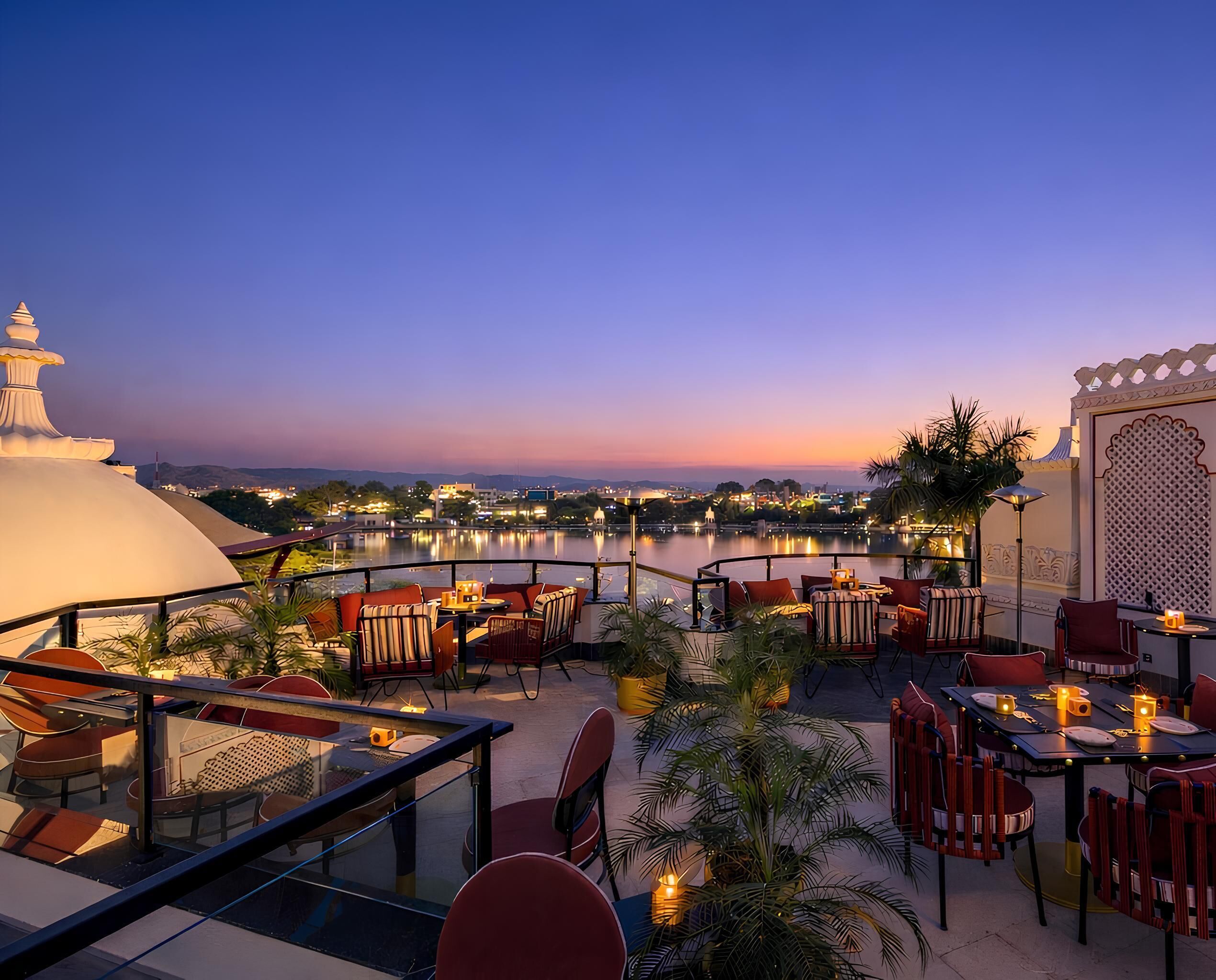A rooftop terrace with outdoor seating, a view of a cityscape, and a body of water.