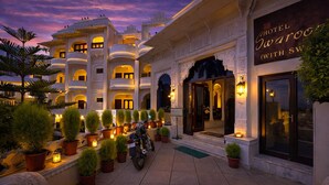 Een hotel met een traditionele architectuur, met meerdere balkons en een goed verlichte entree.