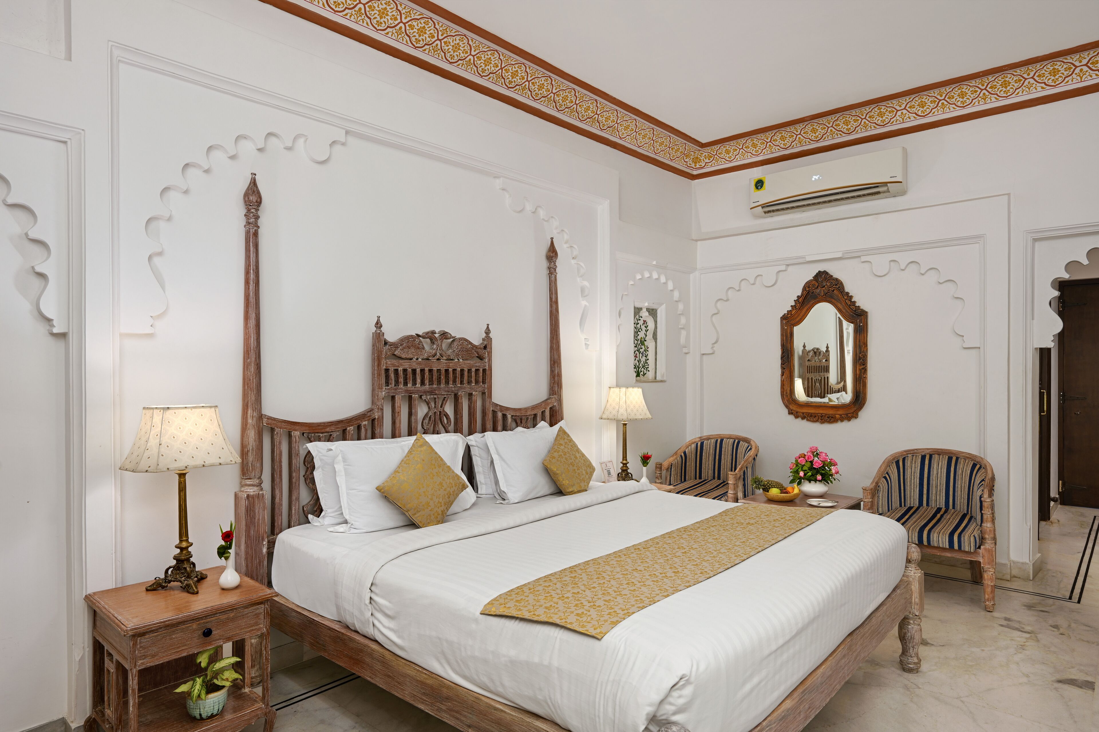 Une chambre bien rangée, avec un grand lit, deux tables de chevet, une chaise et un miroir.