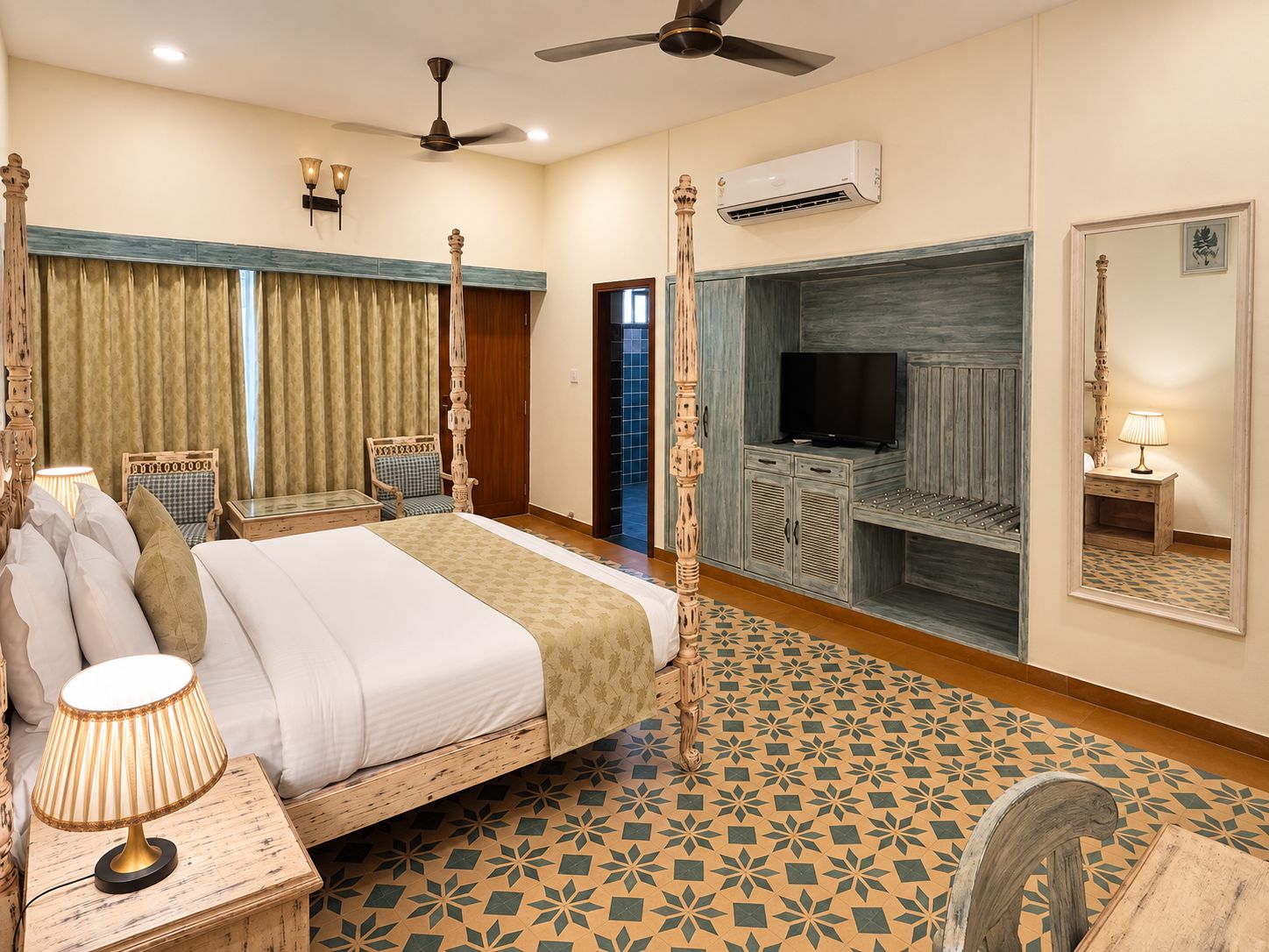 A hotel room with a four-poster bed, a television, a mirror, and a ceiling fan.