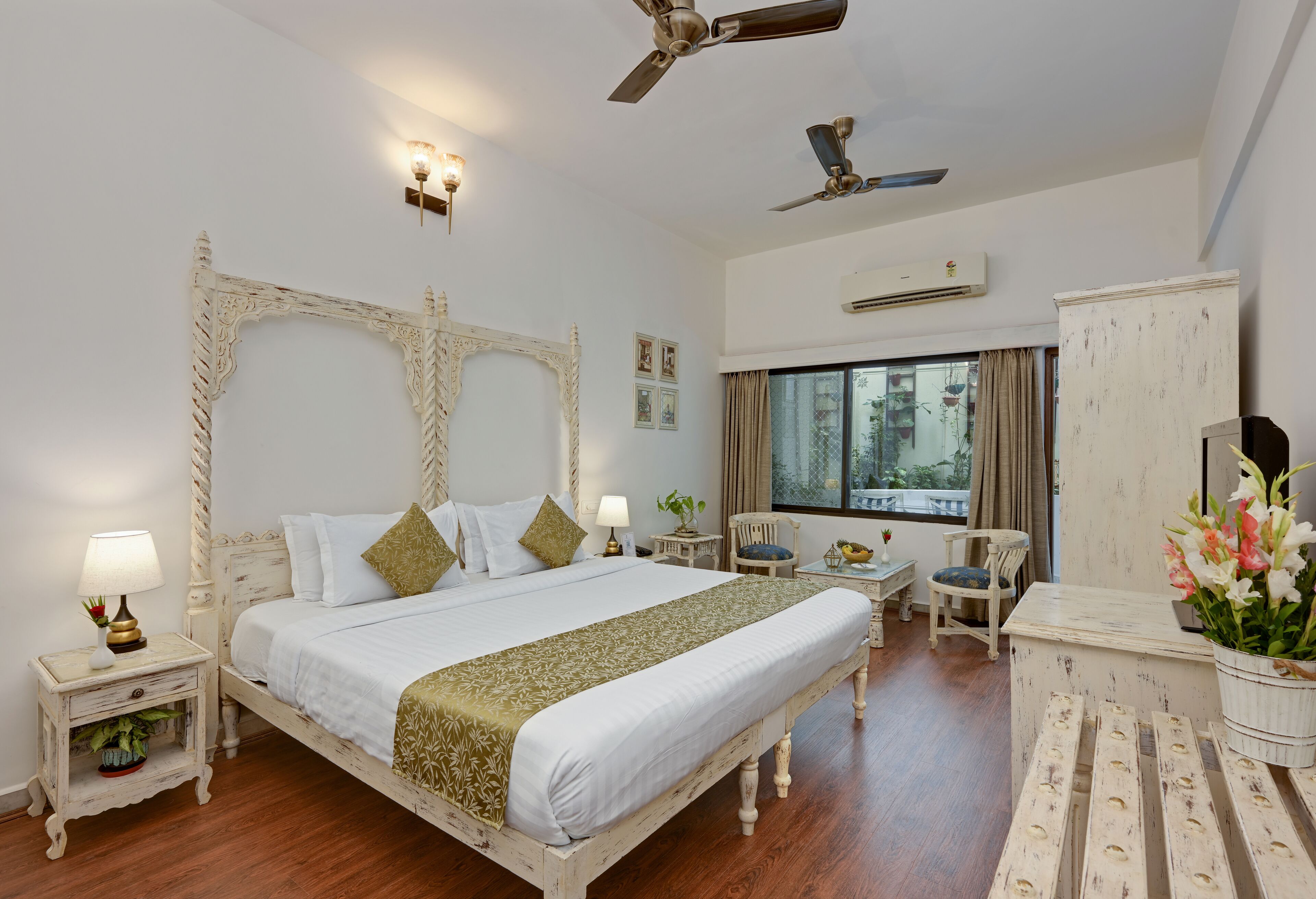 A spacious bedroom with a large bed, two bedside tables, a nightstand, a chair, a desk, and a wardrobe.