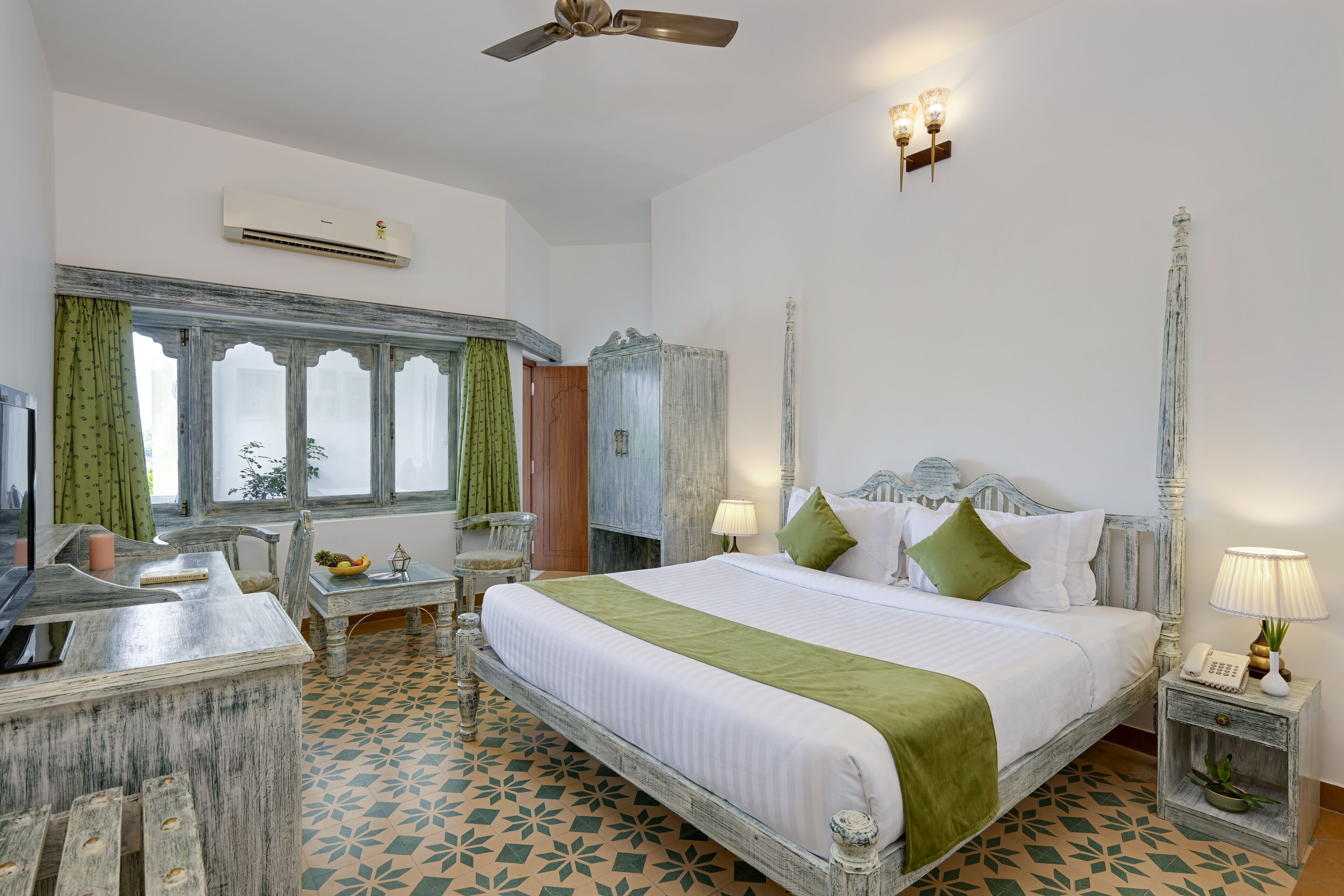 A bedroom with a bed, bedside tables, a desk, a chair, a wardrobe, and a ceiling fan.