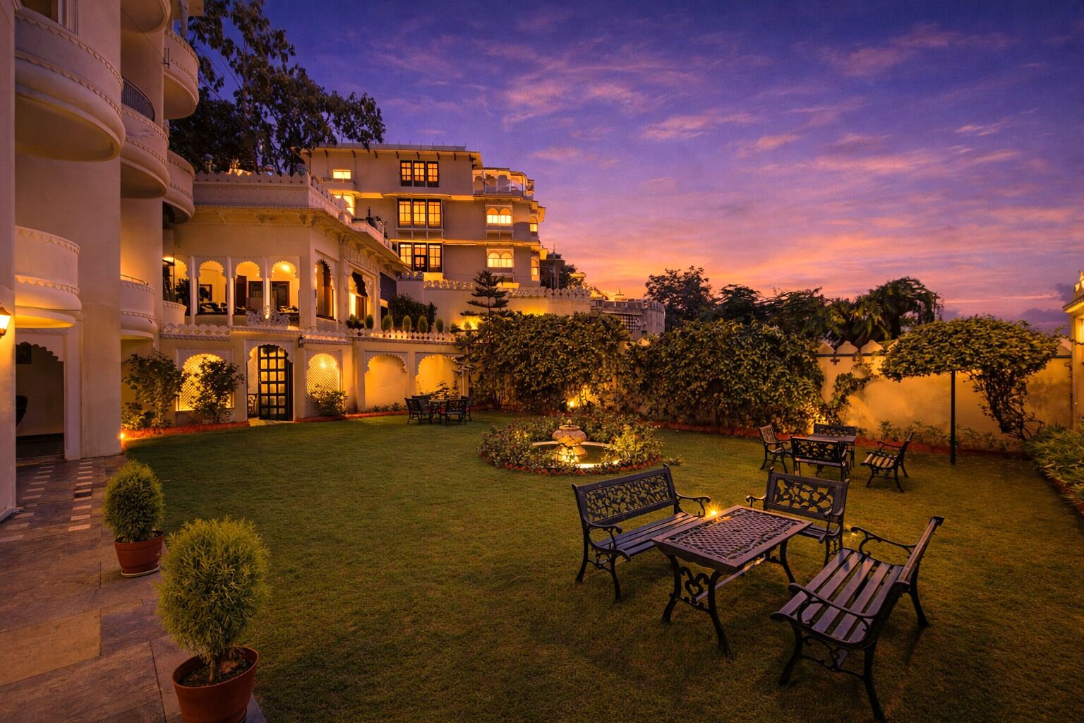 A hotel courtyard with a pool, outdoor seating, and a large building with multiple balconies.