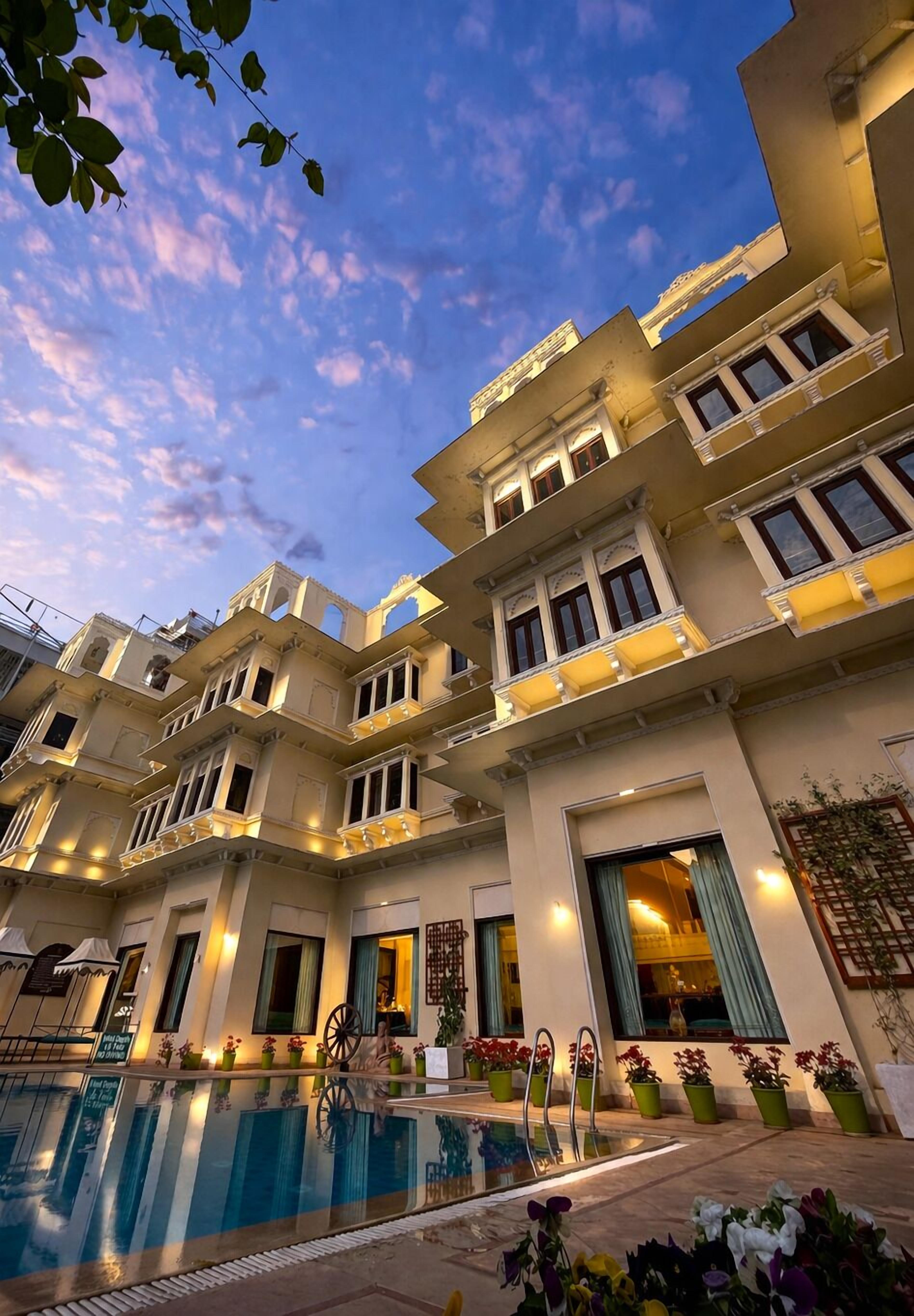 Een meerlaags hotel met een zwembad, balkons en een traditionele architectuur.