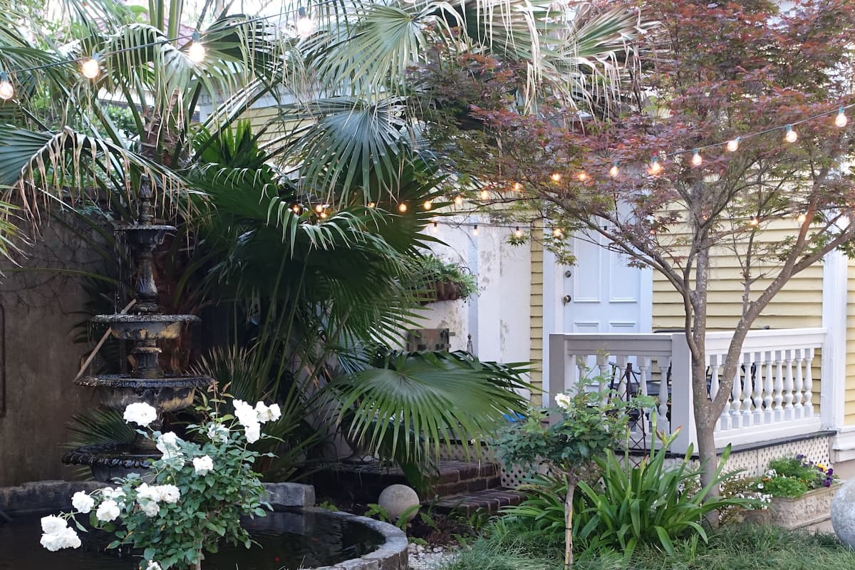 A garden with a fountain, a tree, and string lights.
