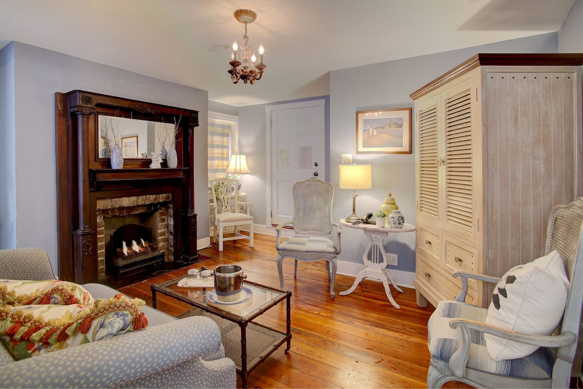 A traditional living room with a fireplace, a chandelier, and classic furniture.