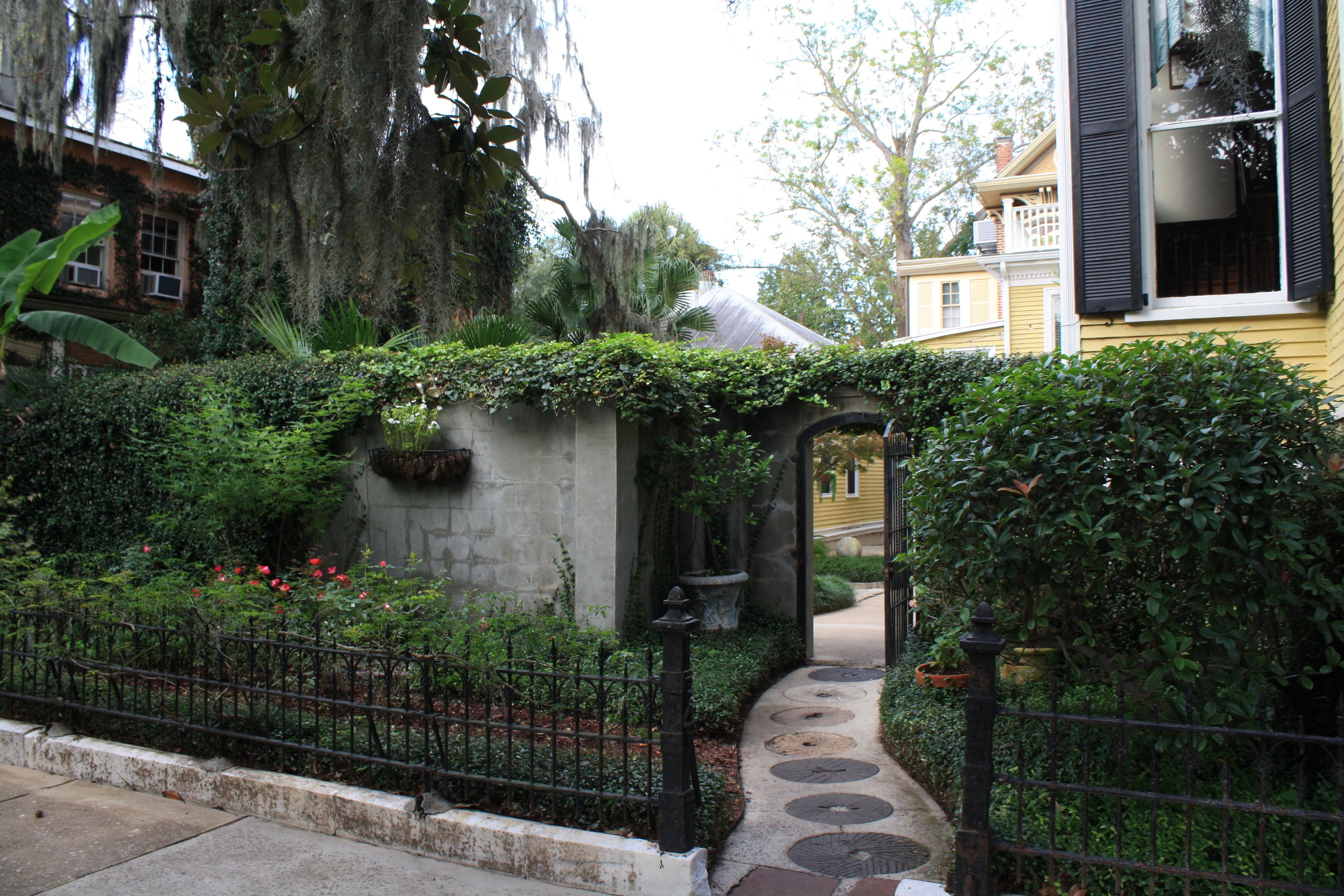 A pathway leading to a building with a stone wall and a small garden area.