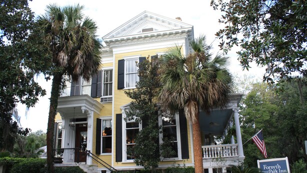 Un edificio giallo con un portico, un'insegna per Forsyth Park Inn e una bandiera americana.