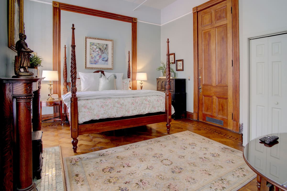 A traditional bedroom with a four-poster bed, wooden furniture, and a large wooden door.