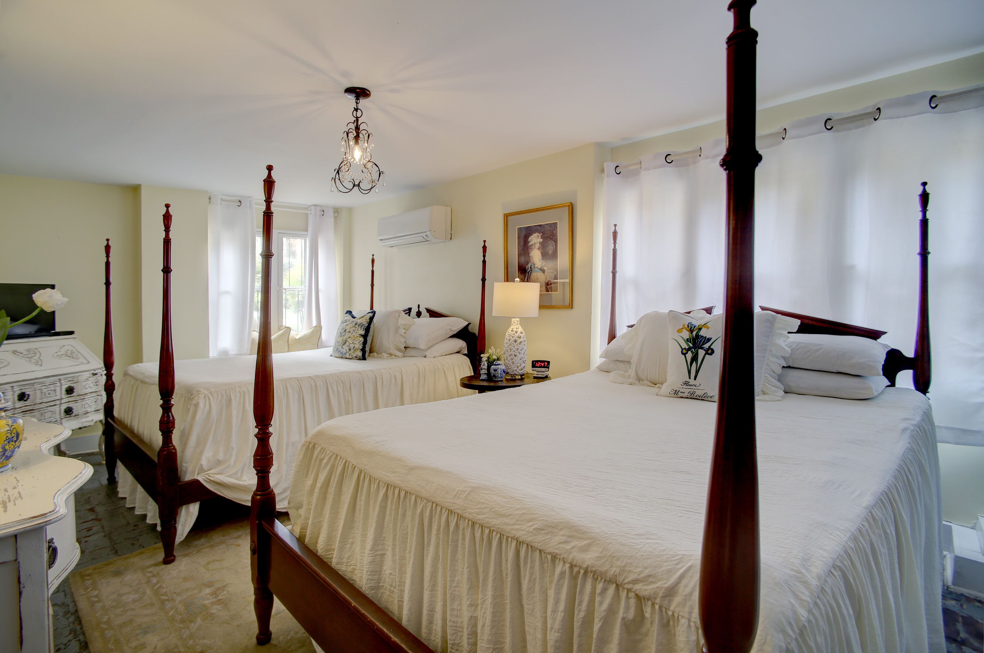 A four-poster bed with a canopy, a bedside table with a lamp, and a dresser with drawers.