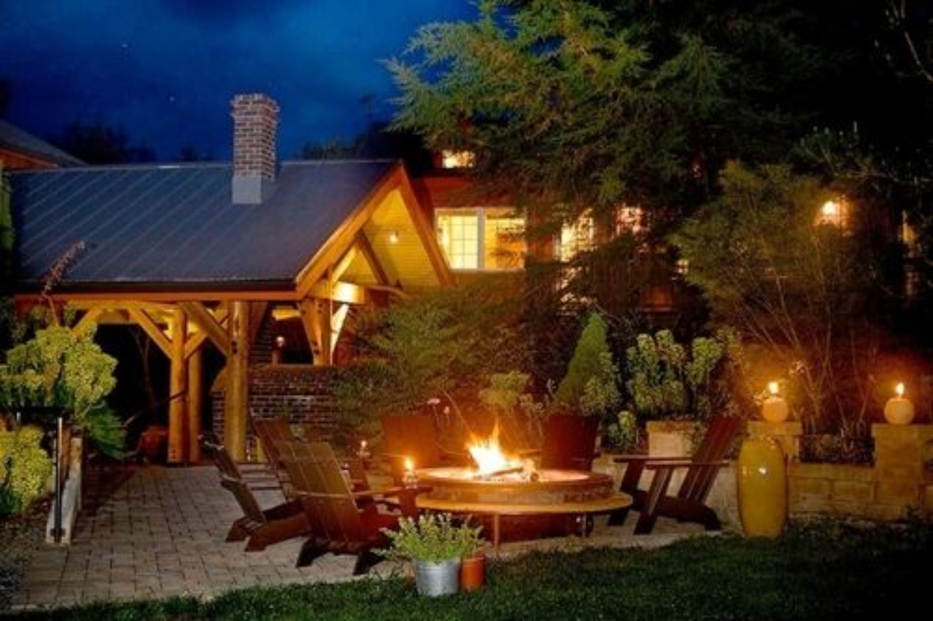 A cozy outdoor patio with a fire pit, lounge chairs, and a wooden pergola.