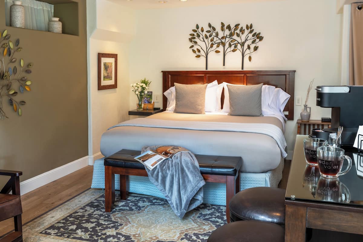 A neatly arranged bedroom with a large bed, bedside tables, a bench, and a coffee table.