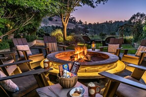 A circular outdoor seating area with a fire pit, surrounded by lounge chairs and a table with snacks. - Eden Vale Inn (Placerville)