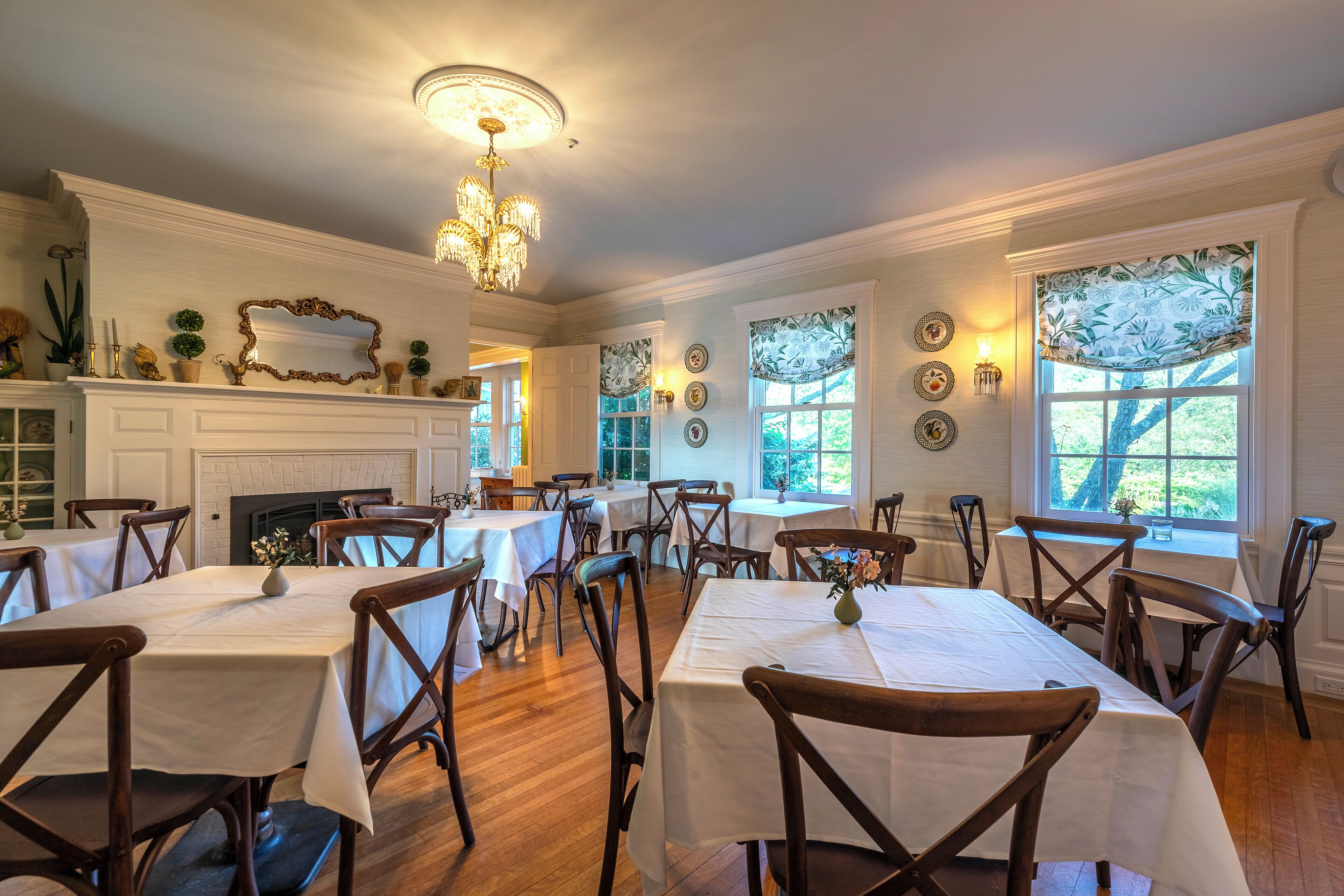 A dining area with multiple tables and chairs, a chandelier, and decorative wall elements.