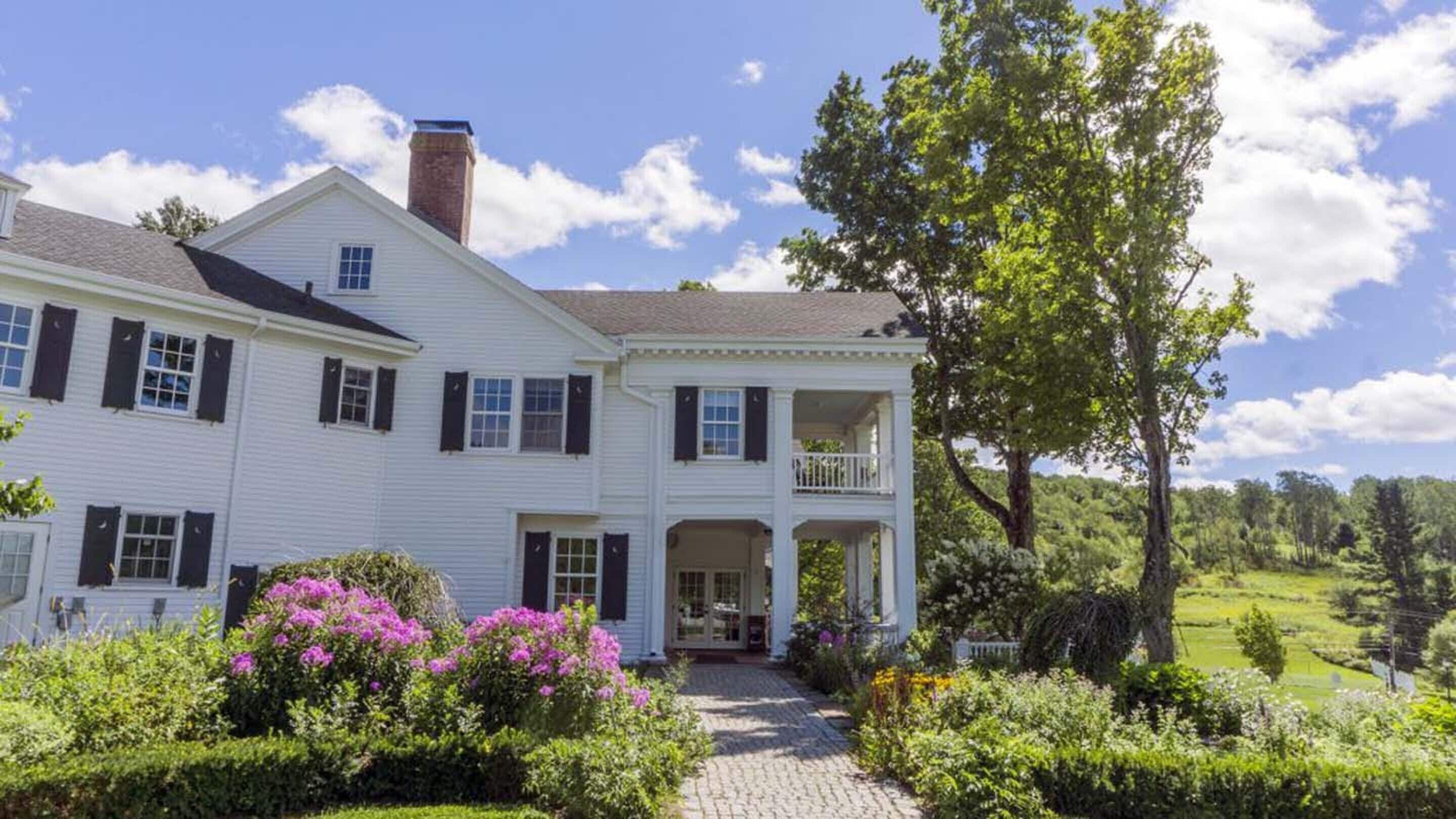 A large white house with a central porch and a chimney.