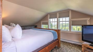 Una camera da letto con un letto grande, una televisione su un mobile in legno e una finestra vista verde.