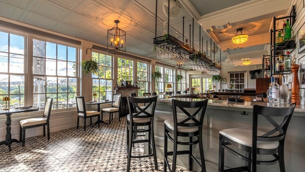 A spacious kitchen with large windows, a bar area, and a dining setup with chairs and tables. - The White House Inn (Wilmington)
