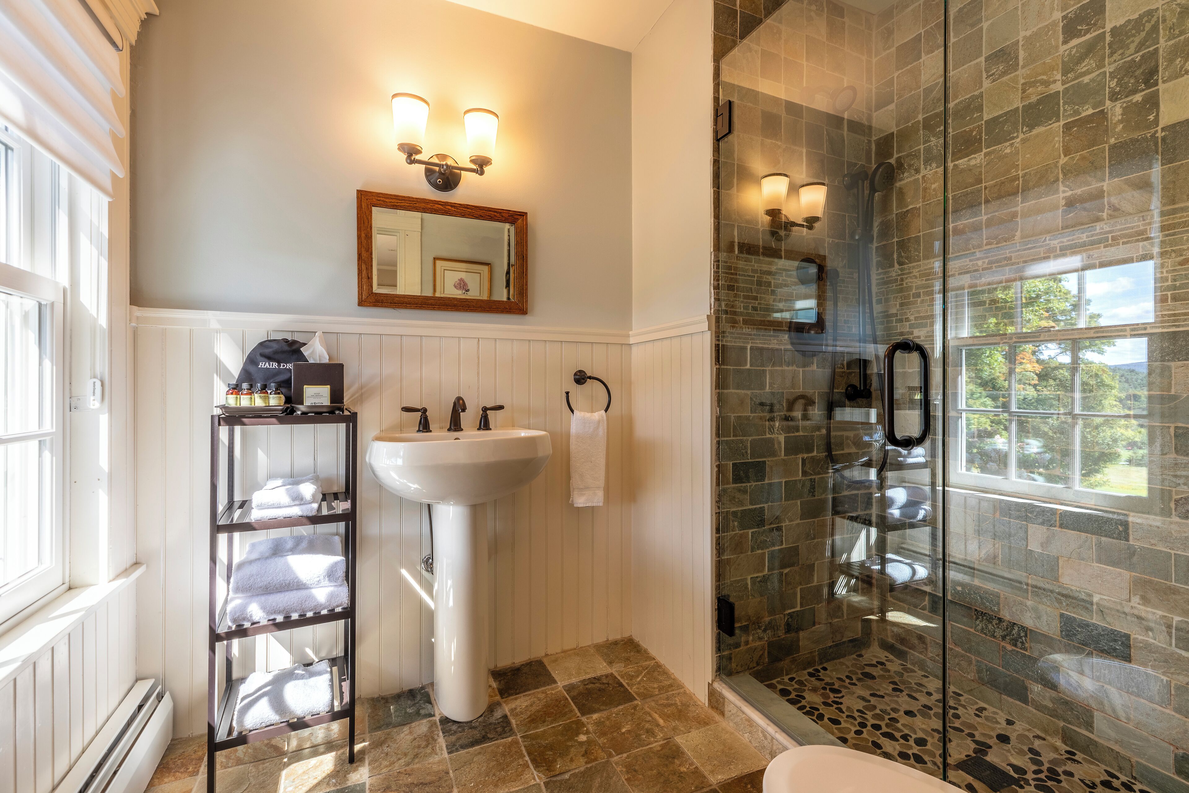 A bathroom with a white sink, a glass shower enclosure, and a towel rack.
