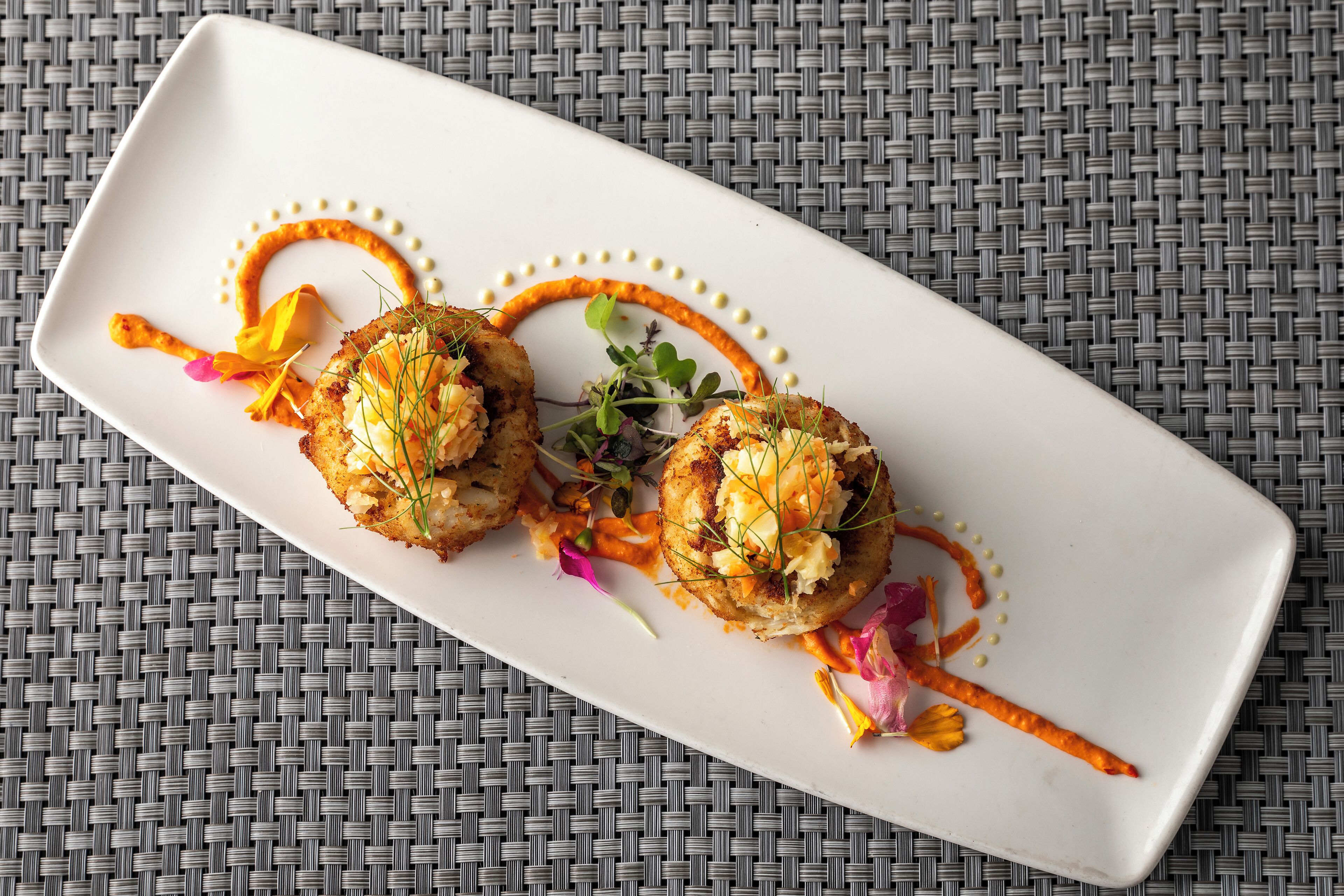 A rectangular white plate with two food items and decorative elements on a woven surface.