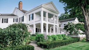 A large, white, two-story house with a central balcony and a covered porch. - The White House Inn (Wilmington)
