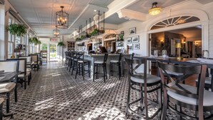 A spacious restaurant with high ceilings, patterned flooring, and multiple seating areas. - The White House Inn (Wilmington)