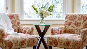 A room with two patterned armchairs, a glass coffee table, a window with a view of trees, and a brown leather bag on the floor. - Healdsburg Inn on the Plaza, A Four Sisters Inn (Healdsburg)