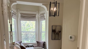 A bedroom with a bed, a window with curtains, a bedside table, and a wall-mounted thermostat. - Healdsburg Inn on the Plaza, A Four Sisters Inn (Healdsburg)