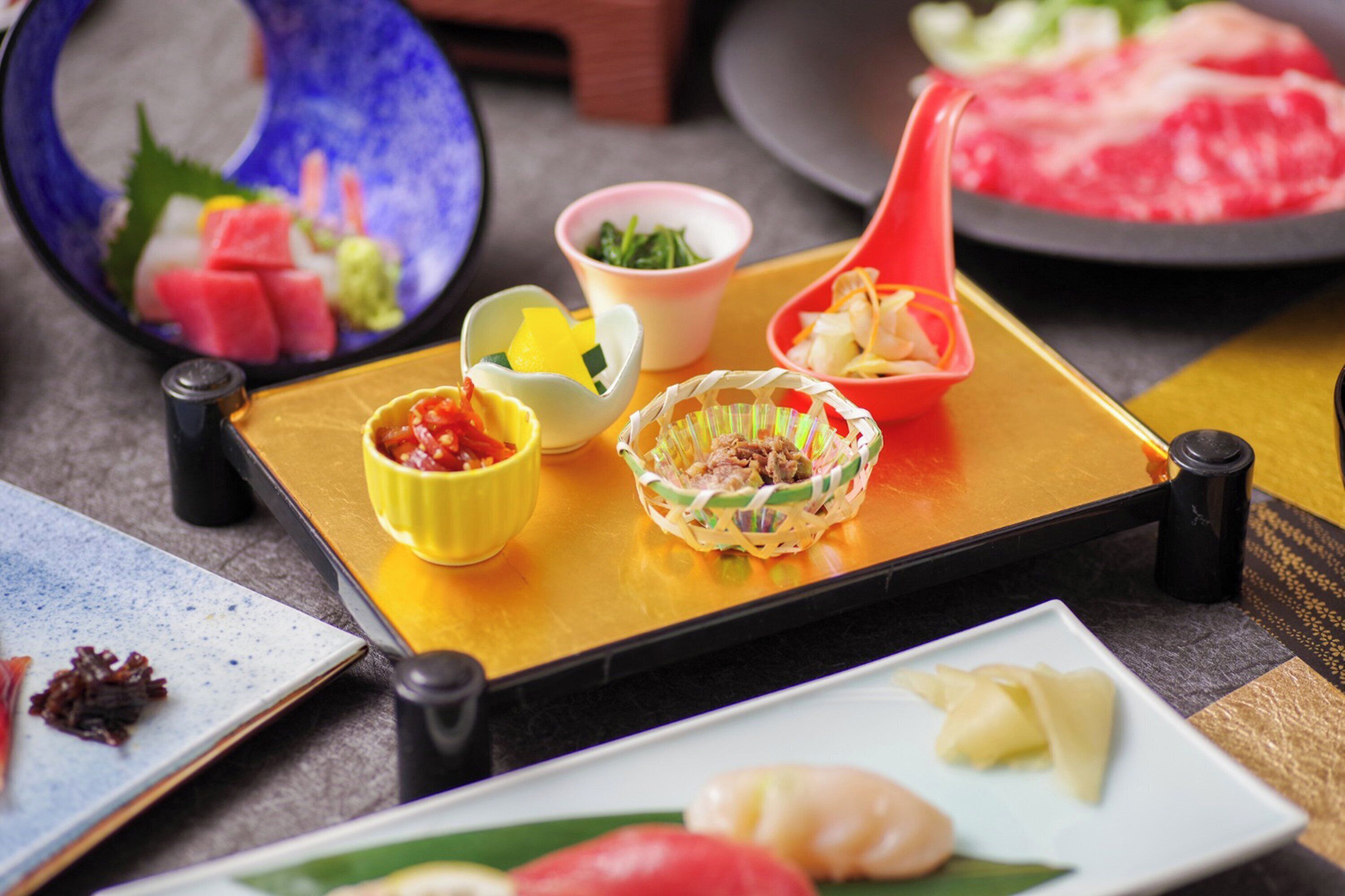 A dining table with various dishes, including sushi and a hot pot.