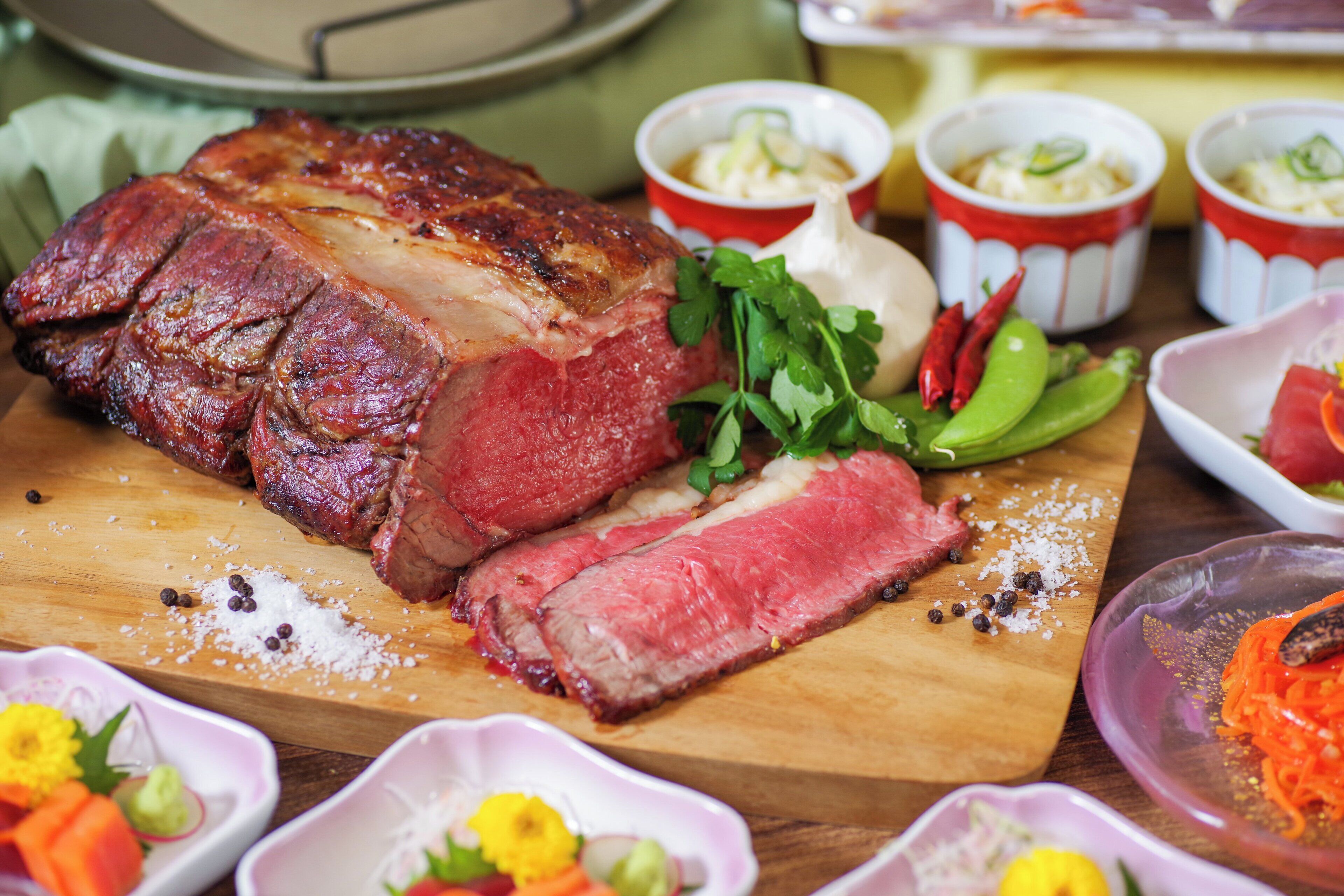 Un plato principal de carne cocida, abundante, sobre una tabla de madera, rodeado de guarniciones y salsas.