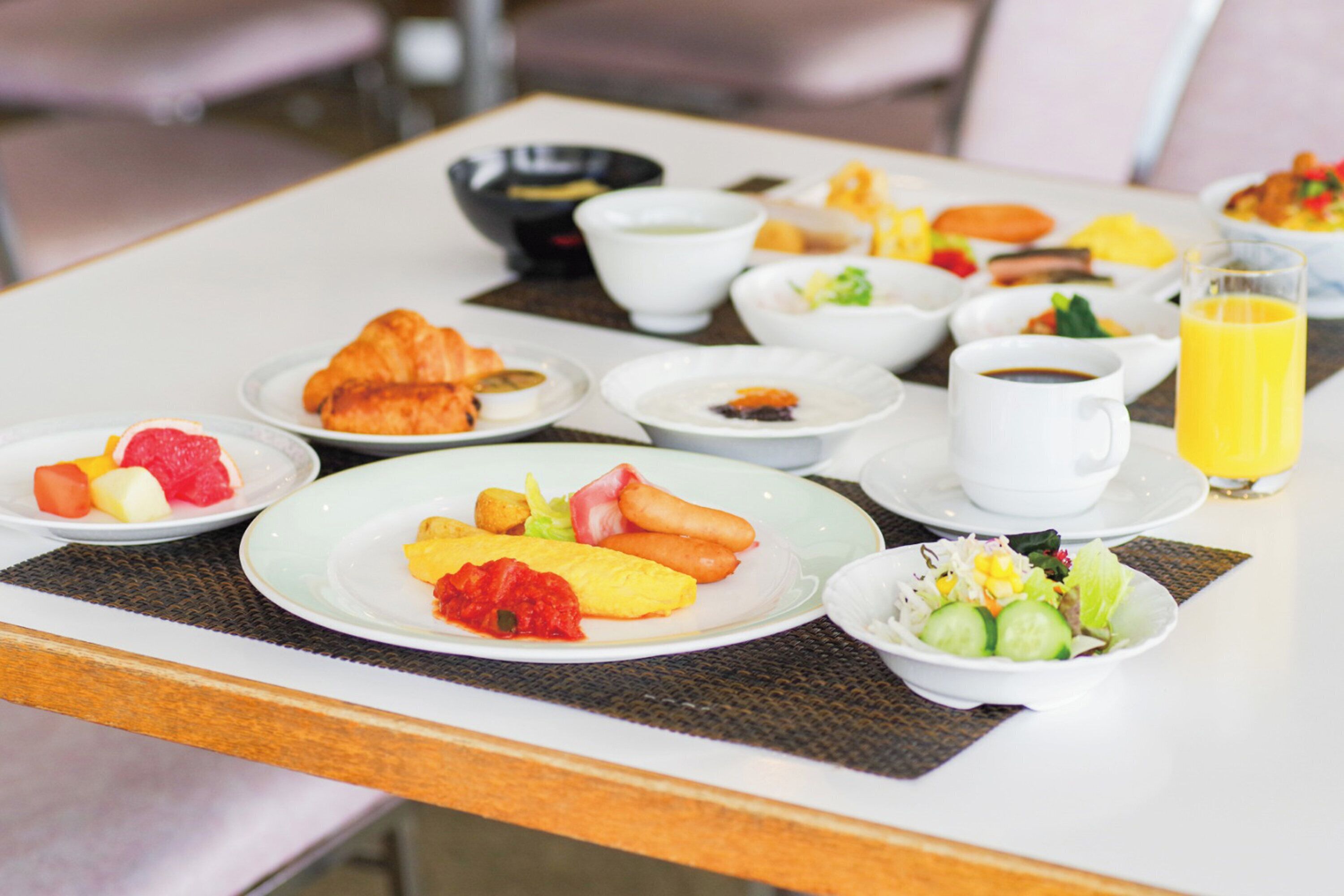 A breakfast table with various dishes including croissants, fruit, and a bowl of soup.