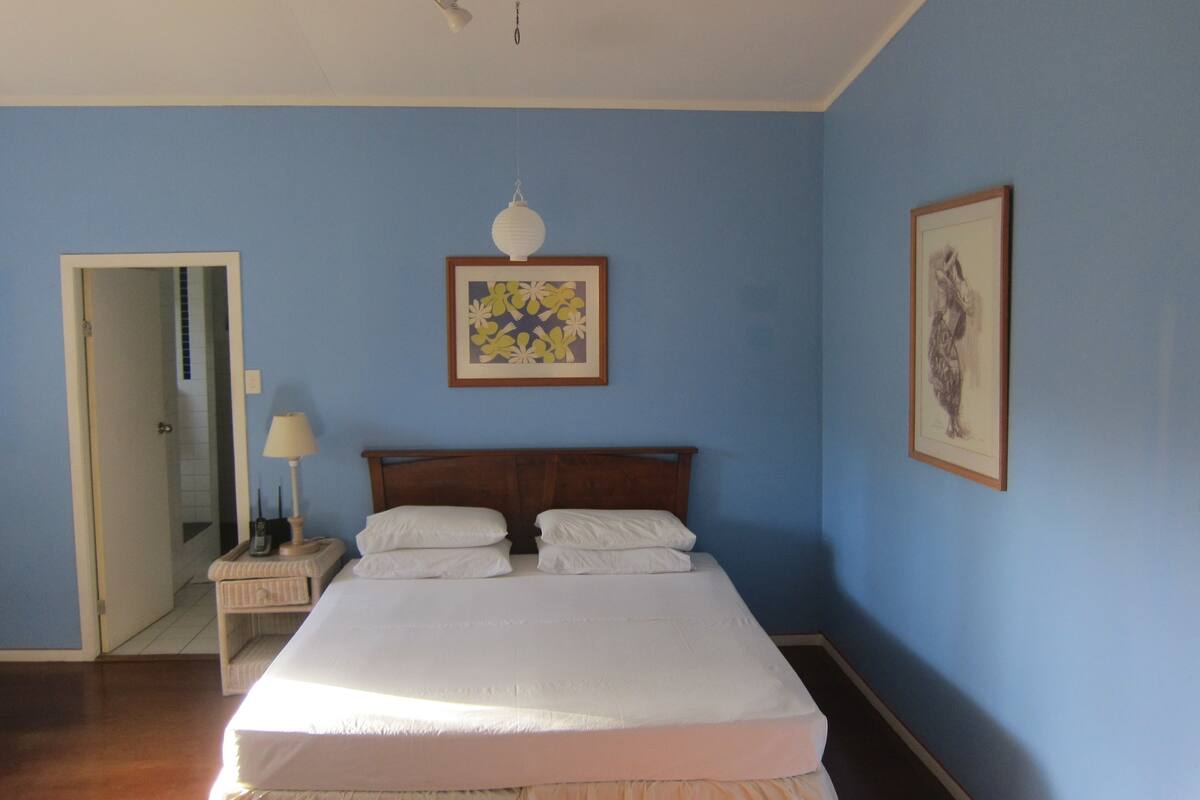 A bedroom with a bed, a nightstand, a lamp, and two framed pictures on the wall.